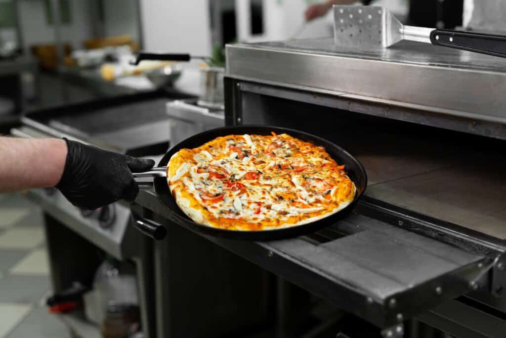 Pizza chef puts pizza in the oven to bake in the oven